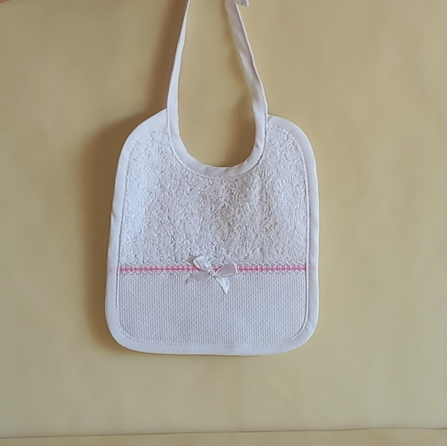 Bavaglino da ricamare a punto croce con fiocco. Stoffa di spugna di cotone con nastro color rosa