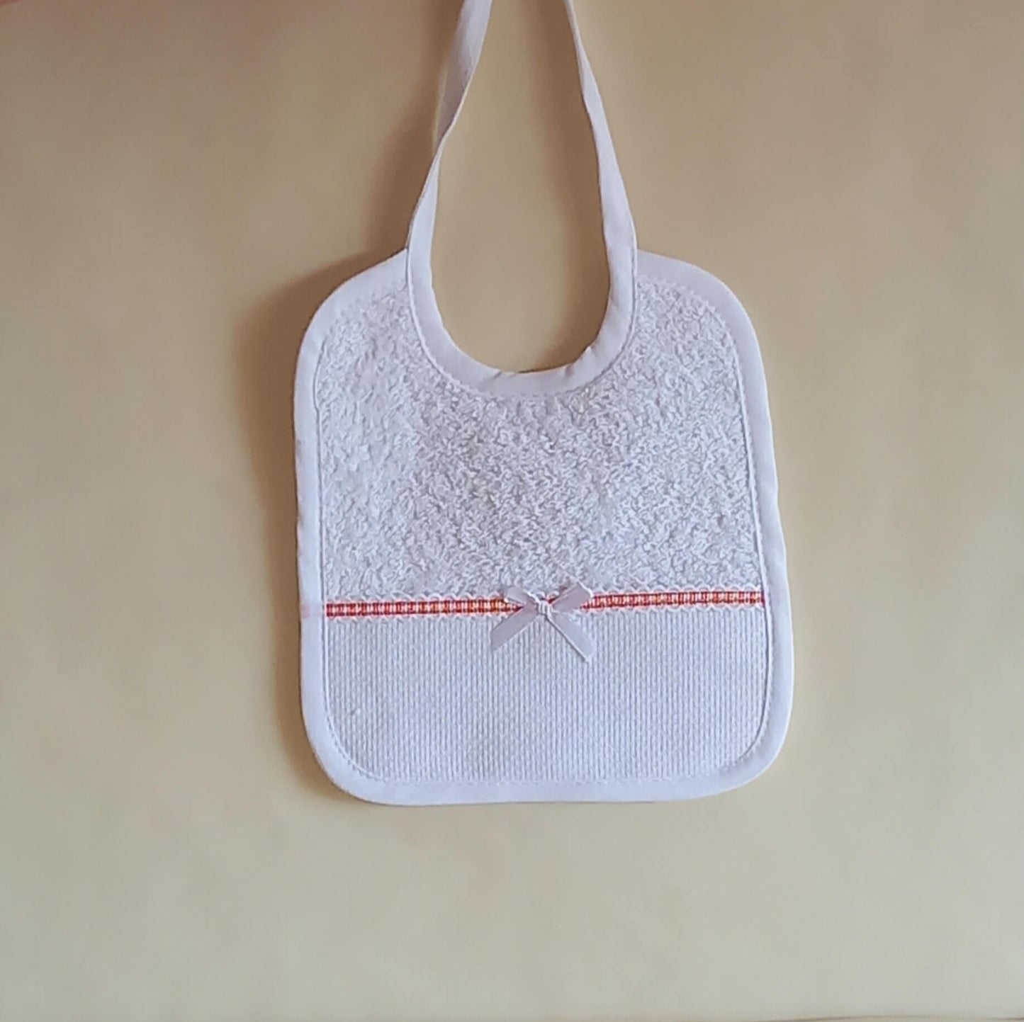 Bavaglino da ricamare a punto croce con fiocco. Stoffa di spugna di cotone con nastro color arancio