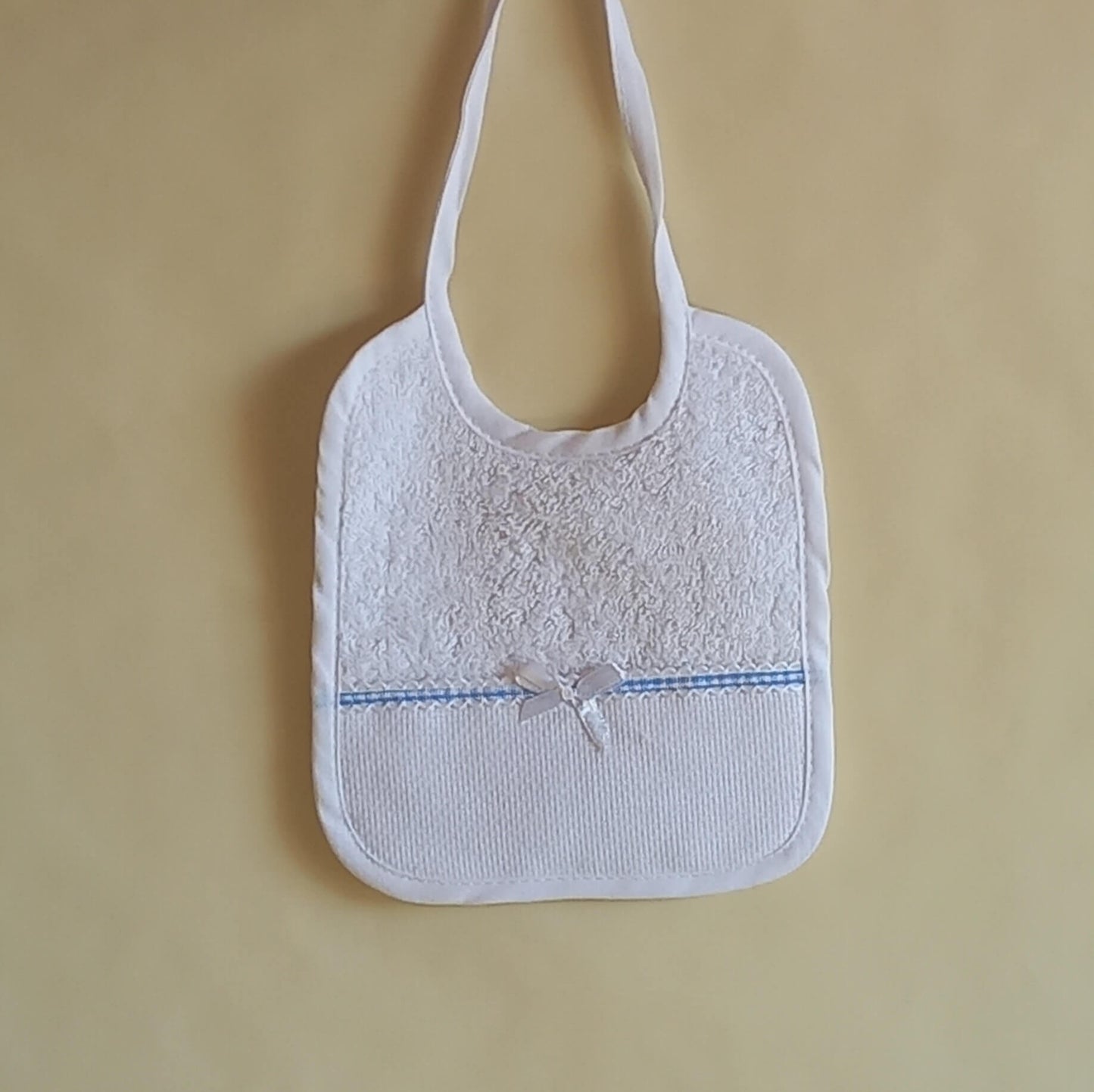 Bavaglino da ricamare a punto croce con fiocco. Stoffa di spugna di cotone con nastro color azzurro